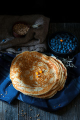 Blintzes or blini - thick russian crepes served with blueberries on dark wooden table. Rustic still life