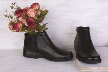 Rose bouquet and black leather shoes on grunge white wood backgr