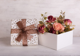 Vintage rose bouquet and gift box on grunge wood background