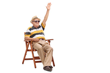 Senior gentleman sitting in a chair and waving