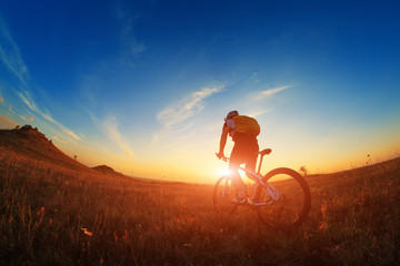 Silhouette of a biker and bicycle on sky background.