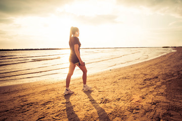 Woman running on the beach at the sunrise