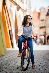 Naklejka premium Urban biking - young woman and bike in city 