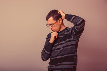 male of European appearance brunet thinking on a gray background