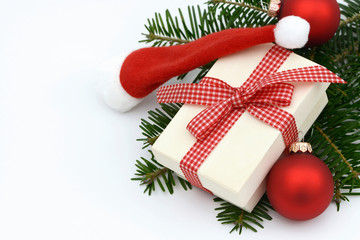 Weihnachtsgeschenk, Weihnachtsmütze und  Kugeln auf Tannenzweig