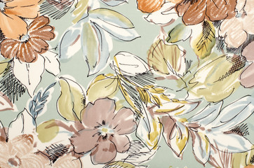 Floral pattern on fabric. Brown flowers with blue and green leaves print as background.