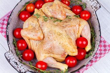 Whole fresh raw chicken prepared for roast with thyme and tomatoes cherry