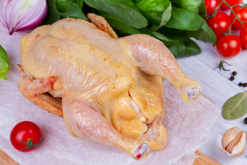 Whole fresh raw chicken prepared for roast with thyme and tomatoes cherry