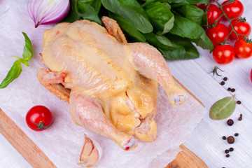 Whole fresh raw chicken prepared for roast with thyme and tomatoes cherry