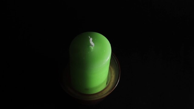 A Green Candle On A Black Background