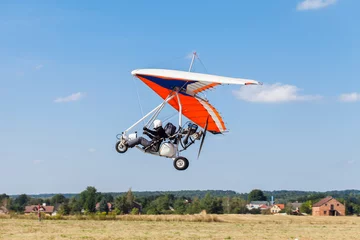 Tuinposter The motorized hang glider over the ground © mariusz szczygieł