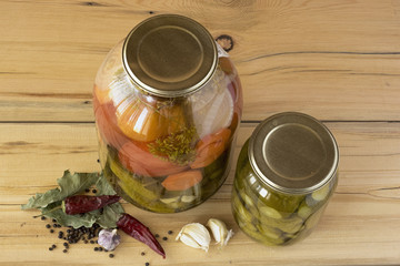 A glass jars with salted cucumbers and tomatoes and some spices