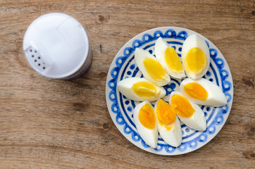 Sliced boiled eggs on a blue decorated plate and salt shaker