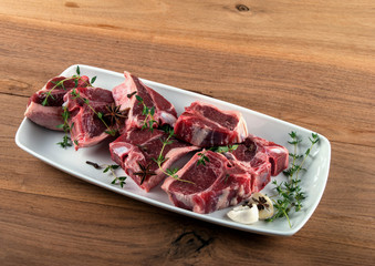 Raw lamb chops with spices and herbs on wooden background