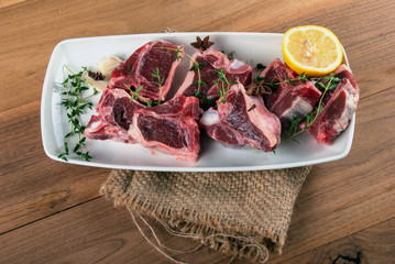Raw lamb chops with spices and herbs on wooden background