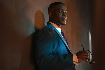 Retro african american businessman in blue suit holding sunglass