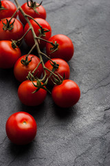 Tomatoes twig on the black stone table vertical