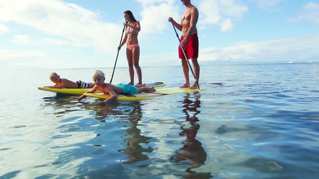Stand Up Paddling in Hawaii. Happy Family of Four. Mother, Father, Two Young Boys. Summer Fun Family Vacation Healthy Lifestyle. Tandem SUP.