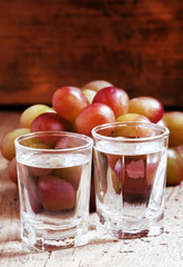 Grappa in a small glass and ripe grapes on old wooden table, sel