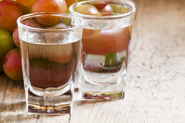 Grappa in a small glass and ripe grapes on old wooden table, sel