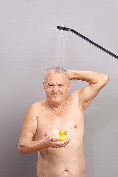 Senior Man Taking A Shower And Holding Rubber Duck