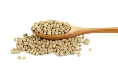 White pepper in wooden spoon on a white background