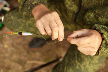 the fisherman attaches the float to the line close-up