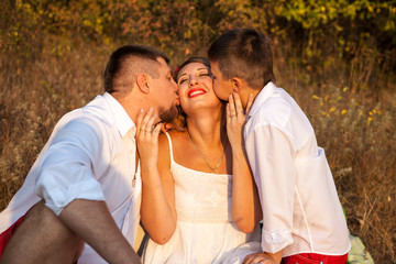 Dad and son kissing his mother on the cheek on both sides