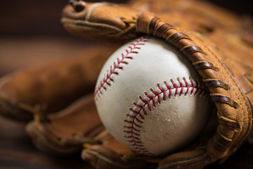 Leather baseball glove and ball on a wooden bench