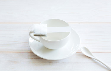 White empty cup with tea bag tea on a white wooden background