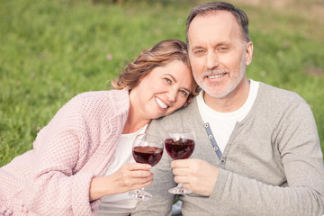 Cute old married couple is enjoying drink in park