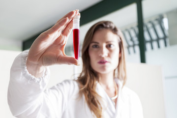 female doctor examines blood tube in laboratory