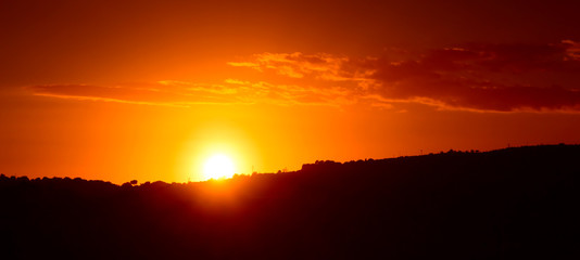 Sole che sta tramontando dietro una collina