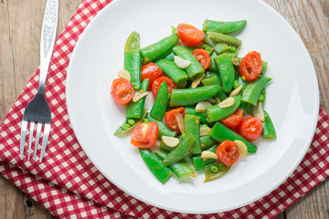 Stir fry sugar snap peas with tomato on napkin.