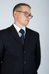 Young serious business man thinking to make a decision. Studio portrait, gray background.