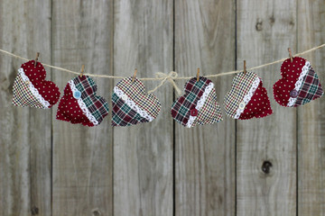 Fototapeta na wymiar Fabric hearts hanging from clothesline with rustic wood background