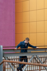 Man in blue suit standing on bridge.
