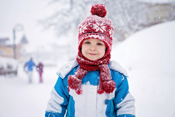 Cute little boy in blue winter suit, playing outdoor in the snow