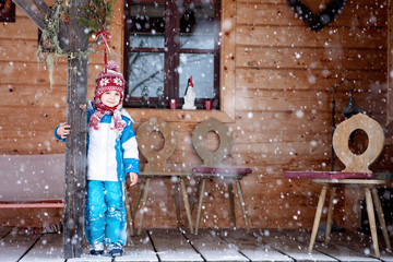 Adorable little boy with lantern, standing in front of a winter