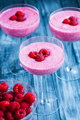 Raspberry mousse in glass on old wooden background. Selective focus.
