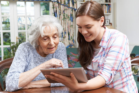 Teenage Granddaughter Showing Grandmother How To Use Digital Tab