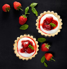 Tartlets with strawberries and vanilla cream on a black background