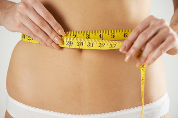 Close-Up Of Woman In Underwear Measuring Waist With Tape