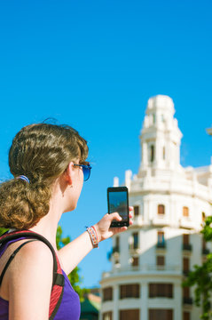 Teen girl tourist  taking picture of historic building in Valenc