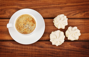Cup of coffee and white cakes on wooden background.