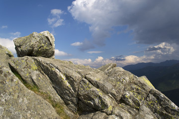Boulder lying on a mountain peak with blue sky background