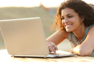 Woman using a laptop in a park at sunset