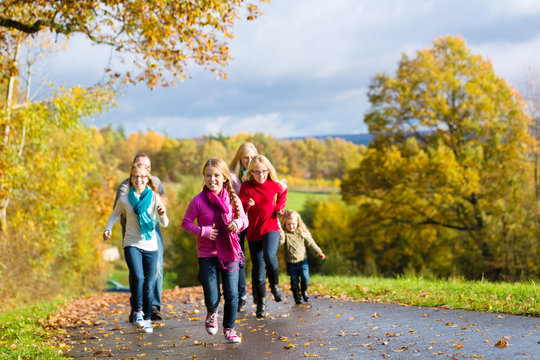 Mädchen rennen bei Familien Spaziergang im Herbst Park vorweg