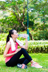 Asian Chinese woman drinking water after sport in park