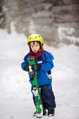 Fototapeta na wymiar Adorable little boy with blue jacket and a helmet, skiing